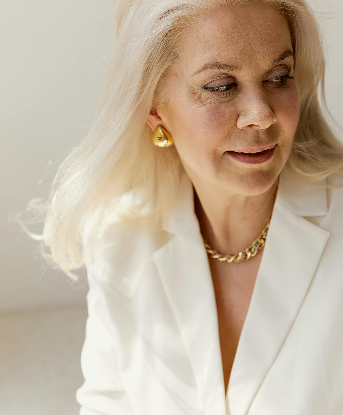 Woman in elegant attire with gold accessories.