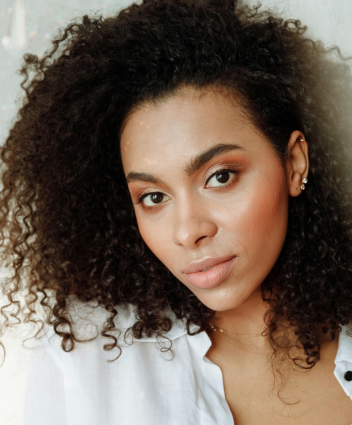 Woman with curly hair and natural makeup.