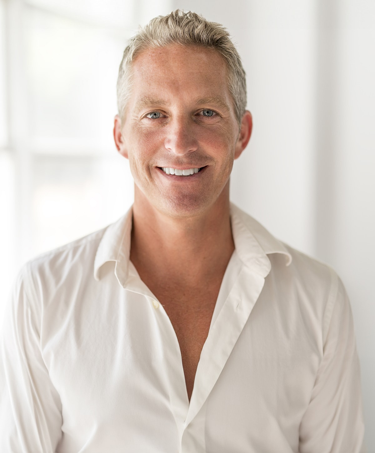 Smiling man in a white shirt, indoors.