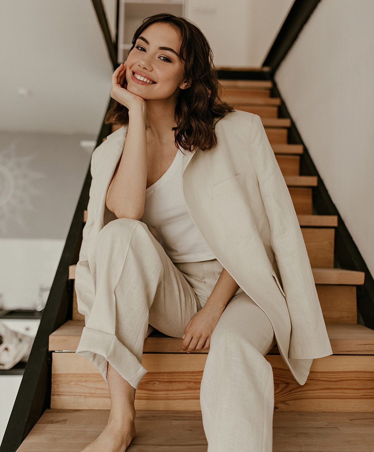 Smiling woman in relaxed, stylish outfit on stairs.