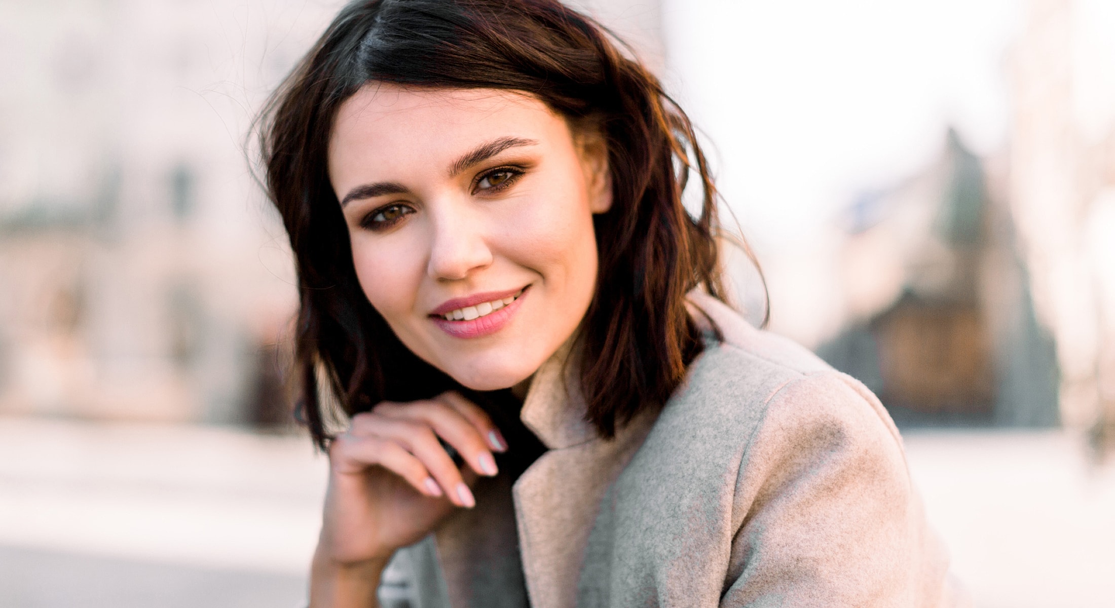Smiling woman with shoulder-length brunette hair outdoors.
