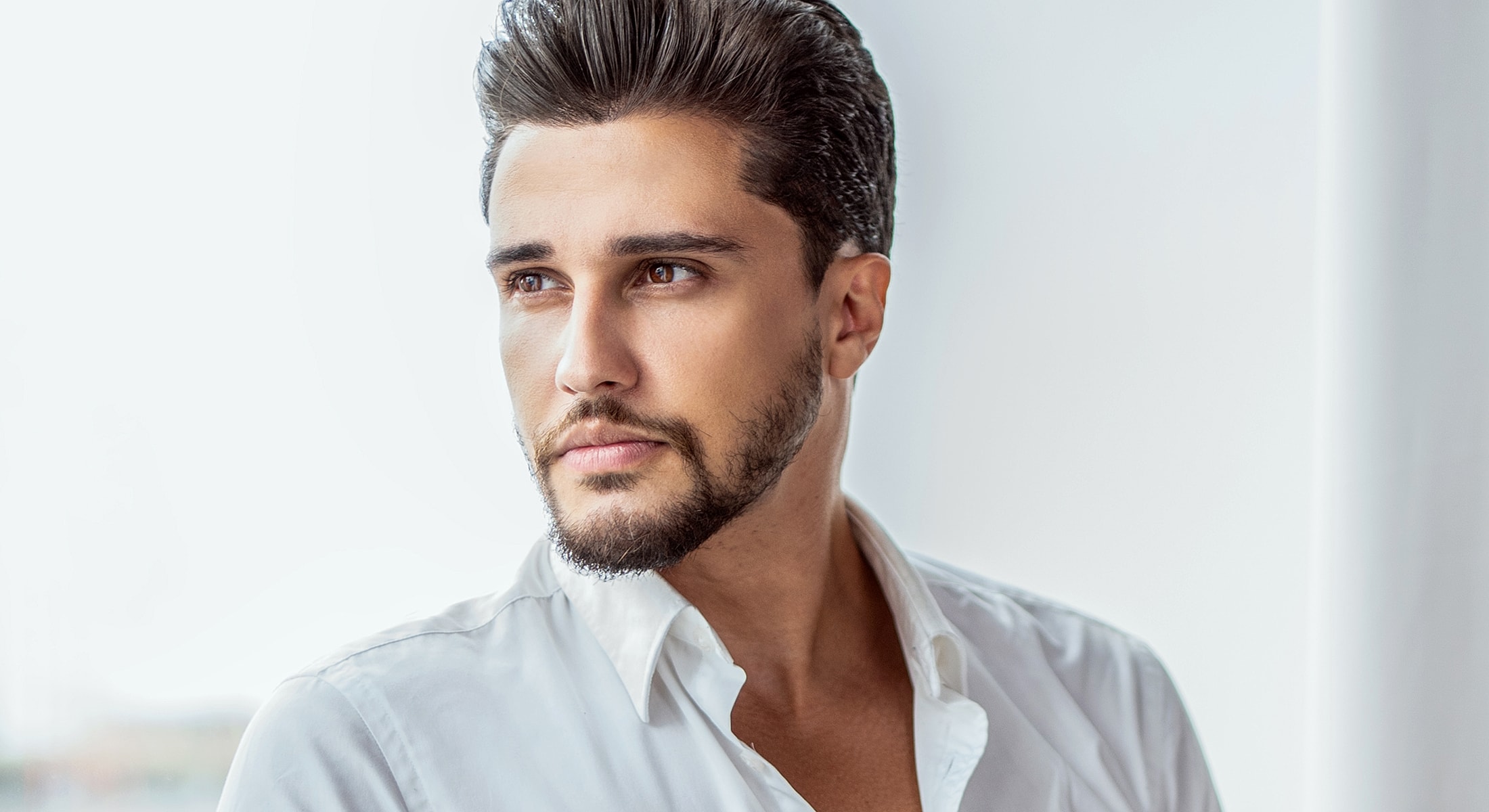 Man with stylish hair looking thoughtfully outwards.