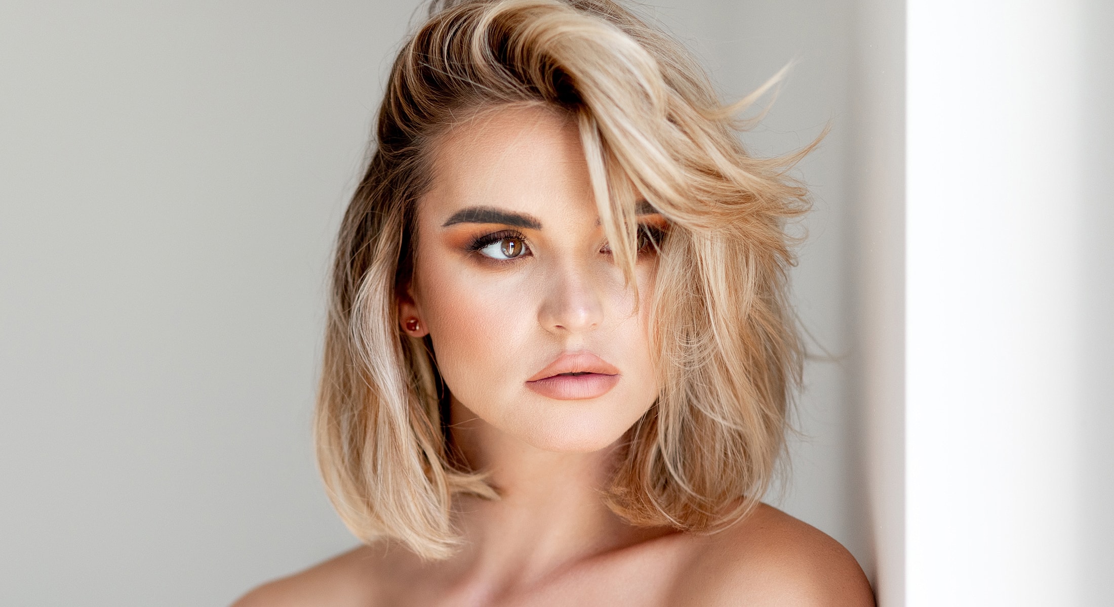 Woman with stylish blonde hair and soft makeup.