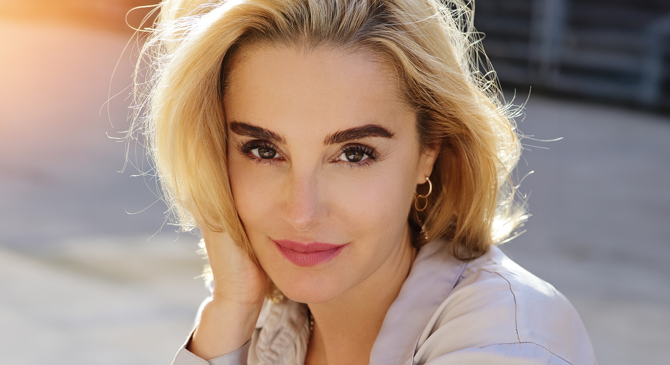 Smiling woman with blonde hair outdoors.